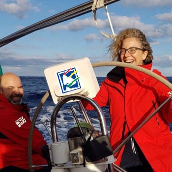 Una mujer y un hombre en un velero con el timón.