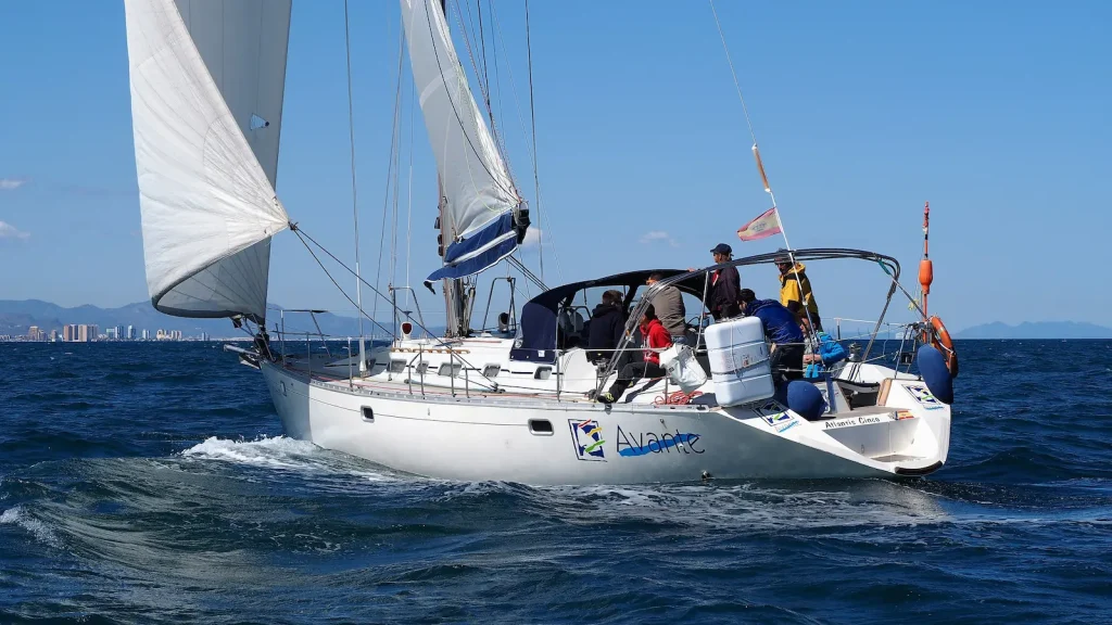velero navegando con tripulantes haciendo las prácticas del per
